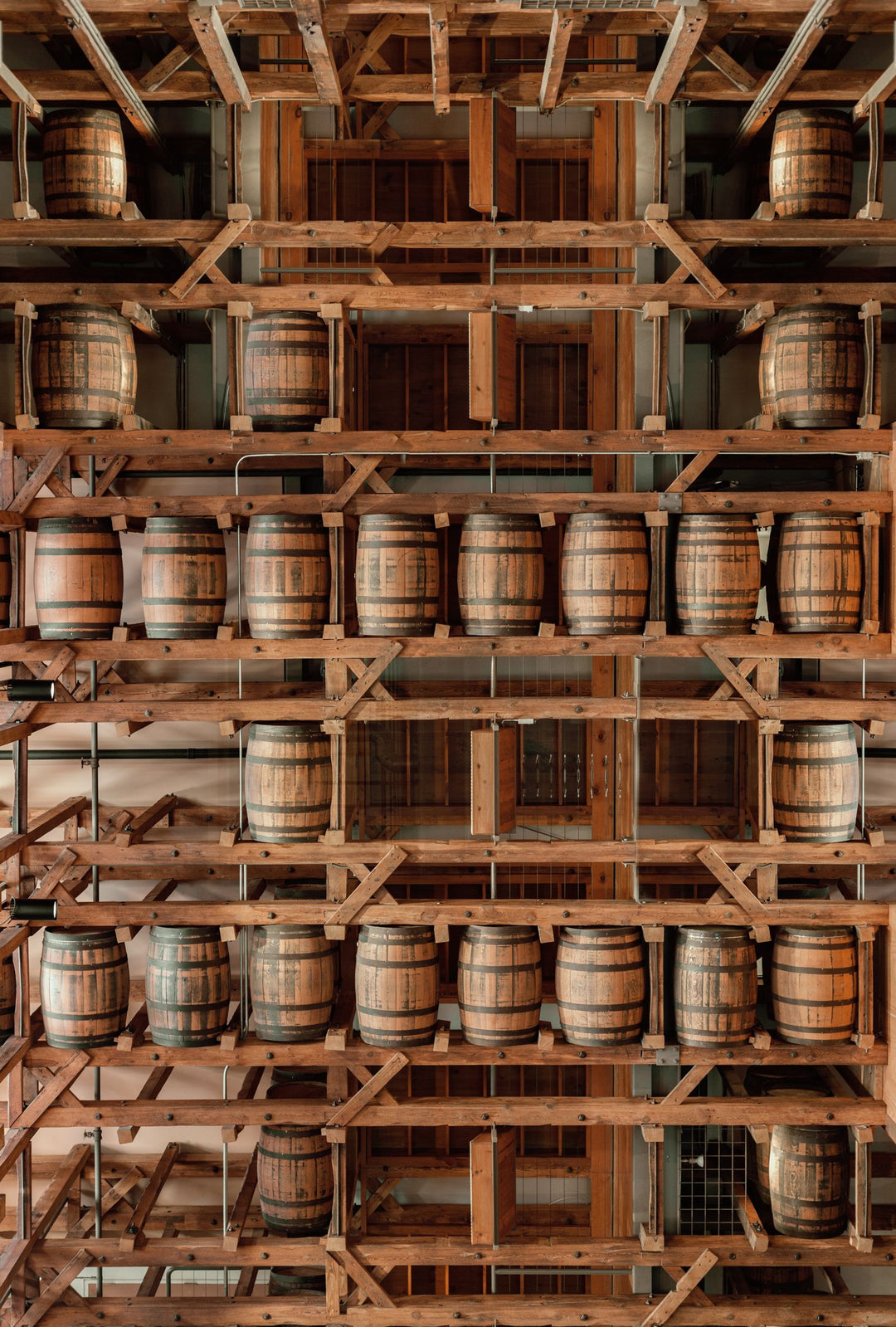 Wooden rum barrels aging on shelves in a distillery warehouse