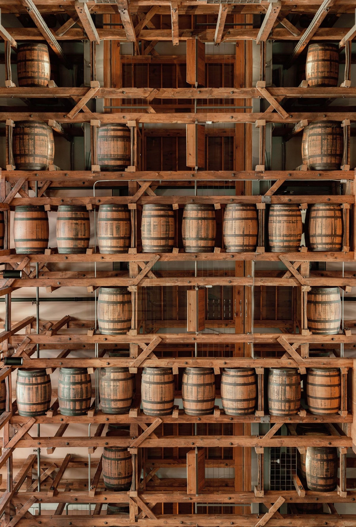 Wooden rum barrels aging on shelves in a distillery warehouse