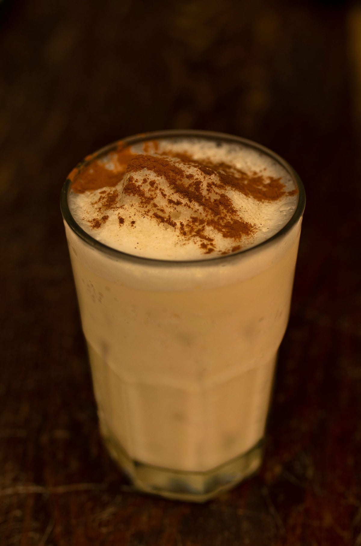 Creamy holiday cocktail topped with cinnamon, in the style of a rum eggnog